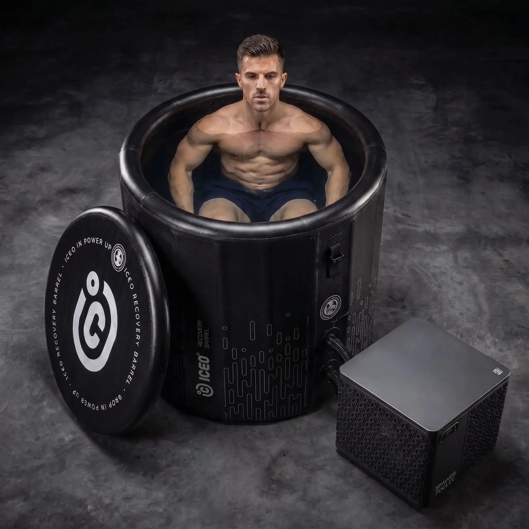 Man zit in de ICEO Recovery Barrel Pro ijsbad met koeler ernaast