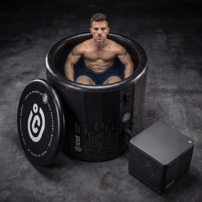 Man zit in de ICEO Recovery Barrel Pro ijsbad met koeler ernaast