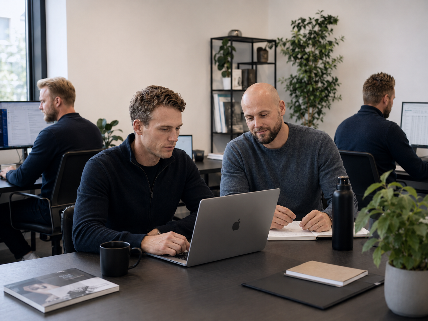 Two ICEO founders work together behind a laptop in the office