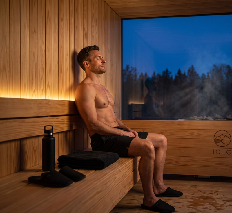 Sportieve man die in de avond in een sauna zit en doet aan warmte therapie