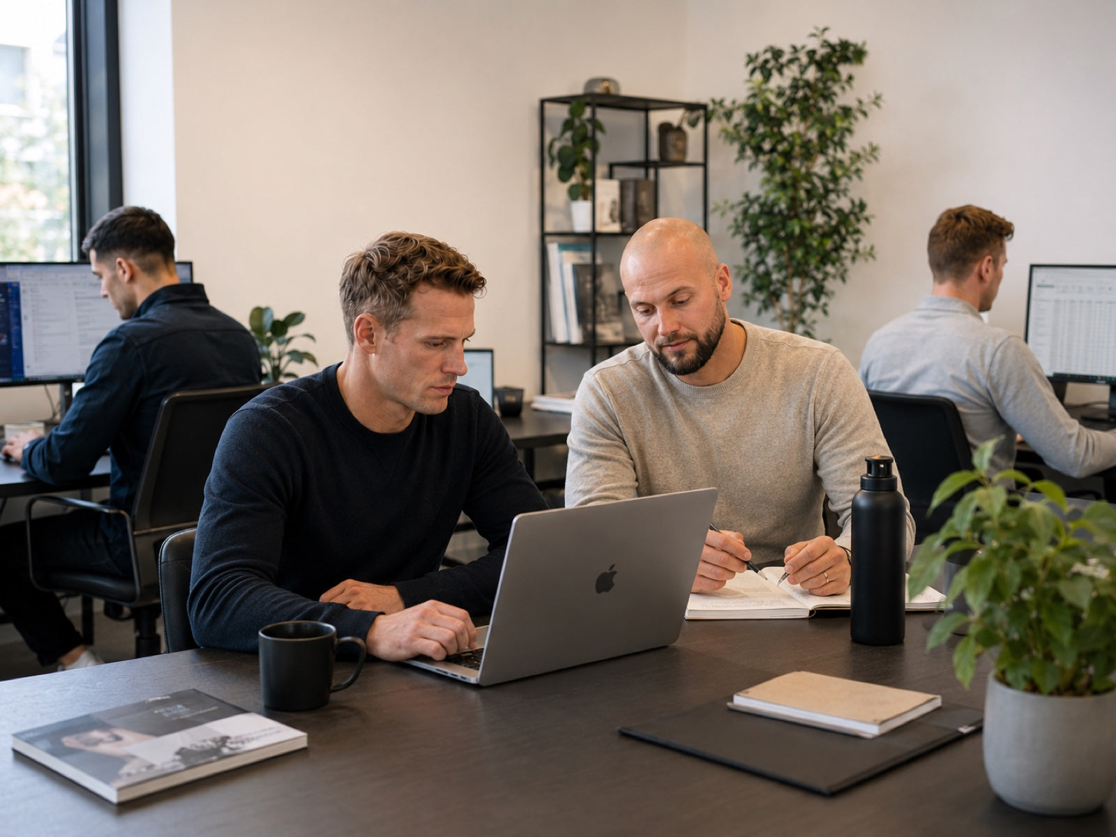 Twee ICEO-oprichters werken samen achter een laptop op kantoor